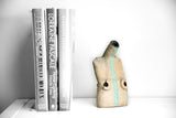 Title: Figure Vessel Artist: Sally Fitchard Medium: clay sculpture Size: 17.8 cm x 9.7 cm x 6.5 cm (in situ, on book-shelf beside books). Colours comprise- natural, black, lichen green