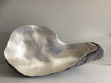 Lucy Gray's 'Shell I' is a large-scale depiction of an oyster shell made from jesmonite and gilded with silver leaf. Photograph of inside of shell.