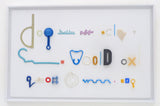 Fiona MacRae's 'Doggerel is an assemblage made from ocean plastic, mounted on white board and framed in a white frame. 