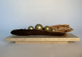 Driftwood with gold spheres on a light surface
