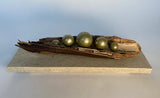 Decorative piece with a driftwood and spherical metallic objects on a stone base
