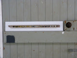 Mixed-media artwork comprising painted driftwood, mounted on a white board and sat on the brace of green/grey door.