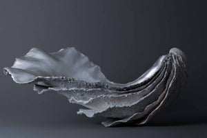 Lucy Gray's 'The Shore of Loch Etive' is a sculpture comprising pigmented jesmonite and silver leaf. In the form of an oyster shell, the artwork reflects the tidal qualities of Loch Etive and its alluring beauty.