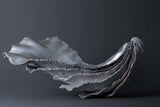 Lucy Gray's 'The Shore of Loch Etive' is a sculpture comprising pigmented jesmonite and silver leaf. In the form of an oyster shell, the artwork reflects the tidal qualities of Loch Etive and its alluring beauty.