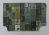 Framed abstract artwork with geometric pattern on a textured white wall