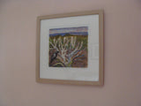 Framed artwork of a bird on a branch against a natural landscape on a beige wall.