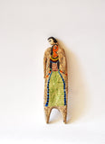 Elham Hemmat's 'Docile Bodies 3' is a ceramic wall sculpture, measuring 18 cm x 5 cm x 1 cm. The artwork is an abstracted human form, decorated with a picture of a woman. Artwork photographed mounted to the wall.
