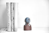 Title: Little Blue Artist: Sally Fitchard Medium: clay sculpture Size: 17.8 cm x 9.7 cm x 6.5 cm (in situ, on book-shelf beside books). Colours comprise- light blue, terracotta, light grey