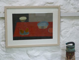 Photo of Fiona MacRae's 'Burn Orange Pear' in situ. The artwork is framed in a wooden frame, painted stone. It is mounted in white and is set behind glass
