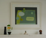 A photo of Fiona MacRae's 'Pea Pod' in situ. The artwork is framed in a wooden frame that is painted off-white. It is also mounted in white and set behind glass