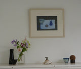 Photo of Fiona MacRae's 'Blue Pear' in situ. The artwork is framed in a wooden frame, painted stone. It is mounted in off-white and set behind glass