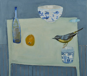 Fiona MacRae 'Yellow and Blue' is an oil painting on paper of a table-top assortment featuring chinaware, a lemon and blue bottle as well as a grey wagtail bird. Colours include blue, grey and yellow.